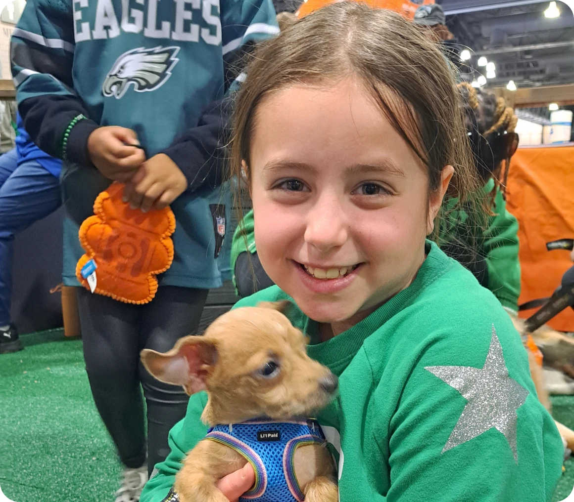 Child in green shirt cuddling a puppy